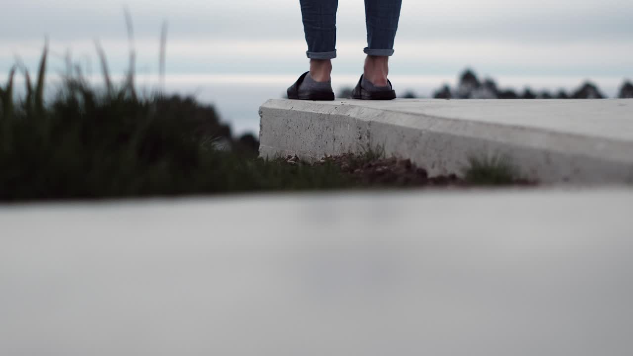 There is nothing more German than wearing Adileten with socks. Man in jeans and sandals with socks looks at the horizon.