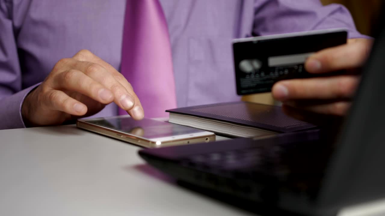 un hombre de negocios con una camisa púrpura y corbata está haciendo un pago a la banca por internet. compras en línea con tarjeta de crédito en el teléfono inteligente.