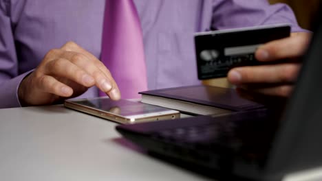 un hombre de negocios con una camisa púrpura y corbata está haciendo un pago a la banca por internet. compras en línea con tarjeta de crédito en el teléfono inteligente.