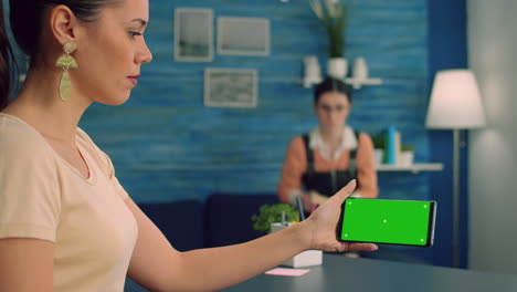 mujer caucásica sosteniendo un teléfono inteligente aislado con pantalla verde simulada