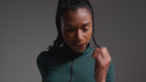 close up studio shot of female athlete wearing tracksuit training running on the spot and recovering after exercise