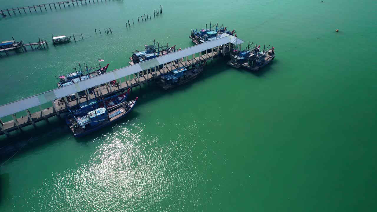 Drone footage capturing fishing boats docked at a rustic jetty in Malaysia