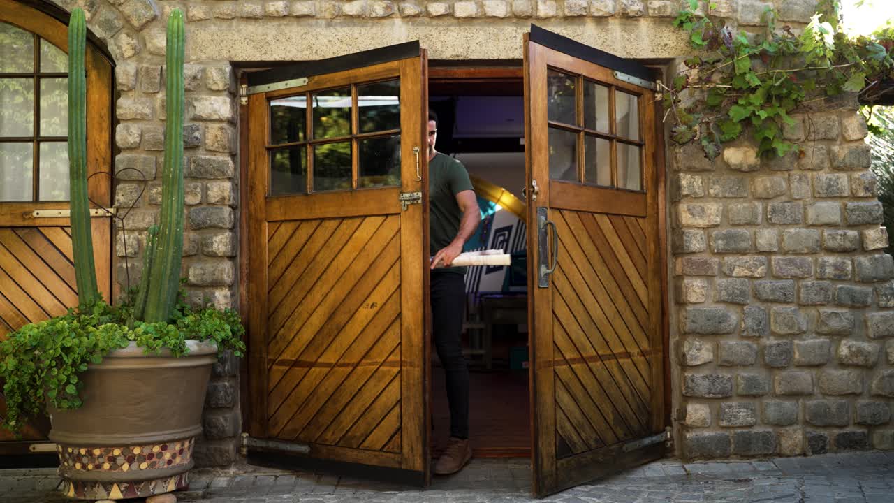 Young male with work papers walking through double wooden doors into an office space