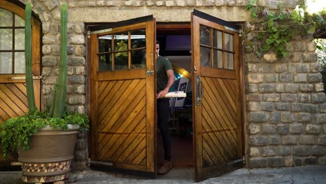 young male with work papers walking through double wooden doors into an office space