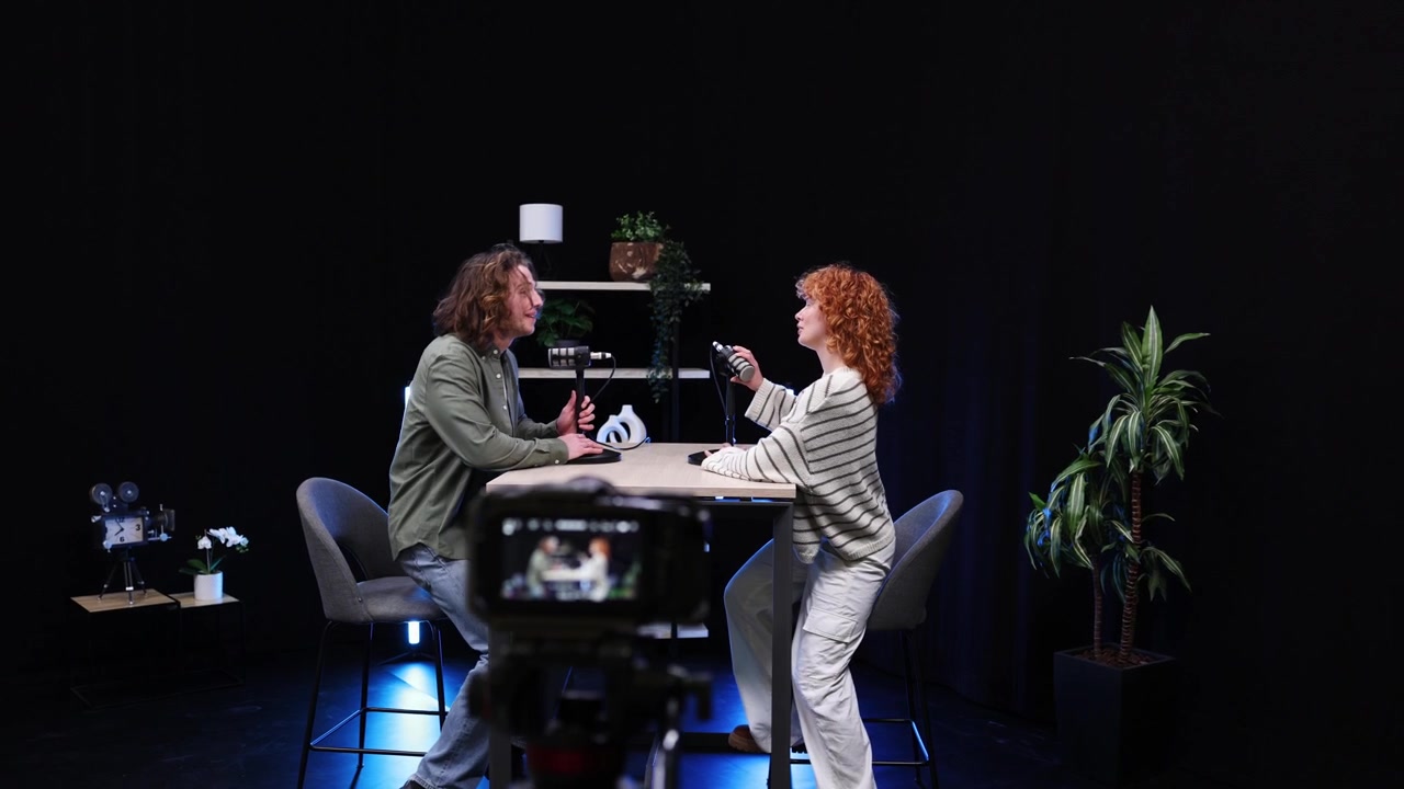 Mand og kvinde forbereder sig til podcastinterview i studie
