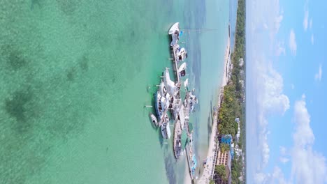 vuelo vertical de drones sobre yates de lujo estacionados en el muelle de la playa de boca chica con aguas claras del mar del caribe