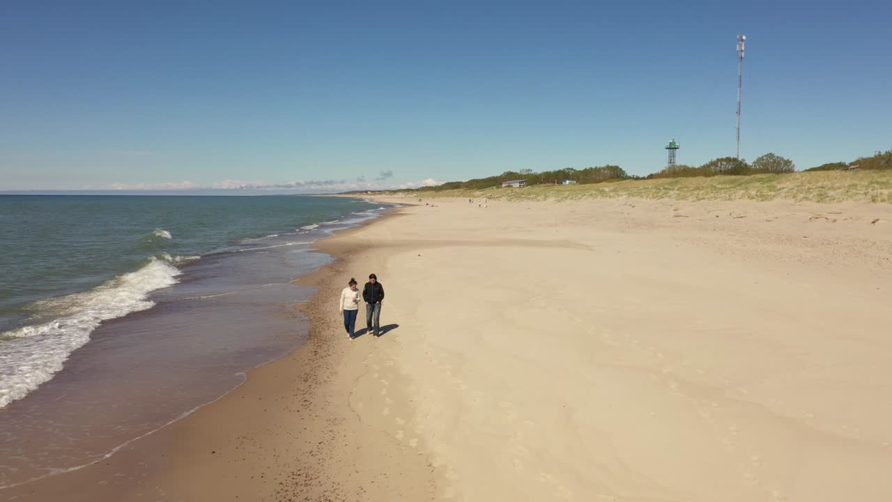 두 명의 여성이 해변을 따라 고 있습니다.