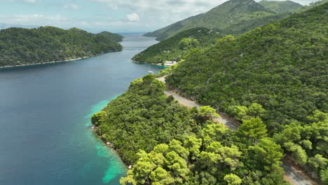 drone dolley shot over the hilly landscape of mljet island where a car drives along the coastal road