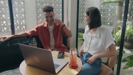 woman speaking with friend over cocktail in cafe