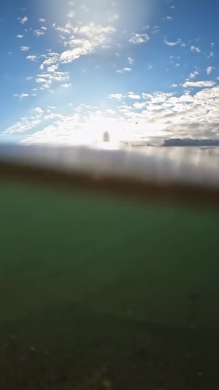 Low-angle video of a serene seascape at sunrise, capturing rippling waves and vibrant sky