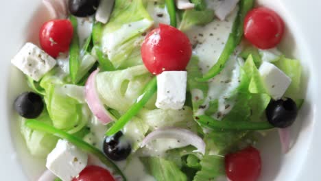 close up of greek salad in a bowl on table