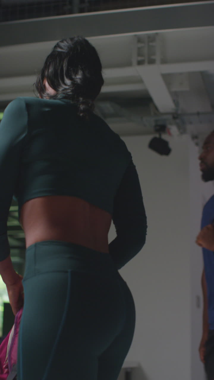 video vertical de atletas masculinos y femeninos en entrenamiento de ropa de fitness en los vestuarios del gimnasio antes o después de la clase de ejercicio 1