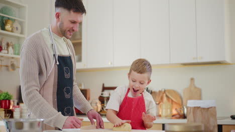 papá y el niño amasan la masa juntos en la cocina