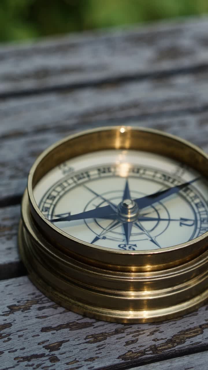 Close-up of a vintage brass compass on a wooden table, shot from a high angle