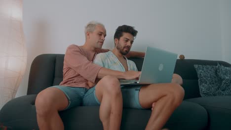 two men using laptop on couch