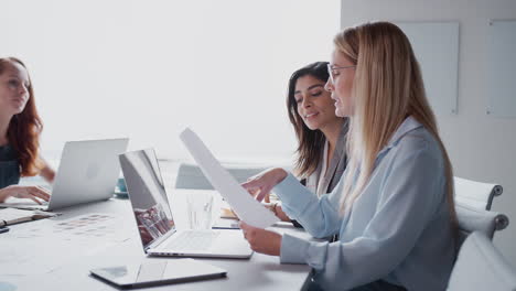 Ein-Team-Junger-Geschäftsfrauen-Trifft-Sich-Am-Tisch-Und-Bespricht-Dokumente-Oder-Pläne-In-Einem-Modernen-Arbeitsbereich