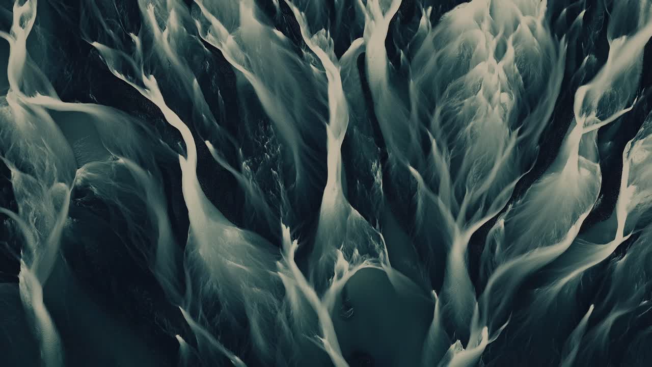Aerial top down timelapse of a braided river system flowing dynamically with intricate natural patterns and surreal motion.