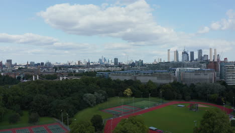 Landing-footage-in-Battersea-Park.-Aerial-with-of-modern-sport-areas.-Cityscape-with-skyscrapers-in-background.-Tilt-down-reveal-of-ground.-London,-UK