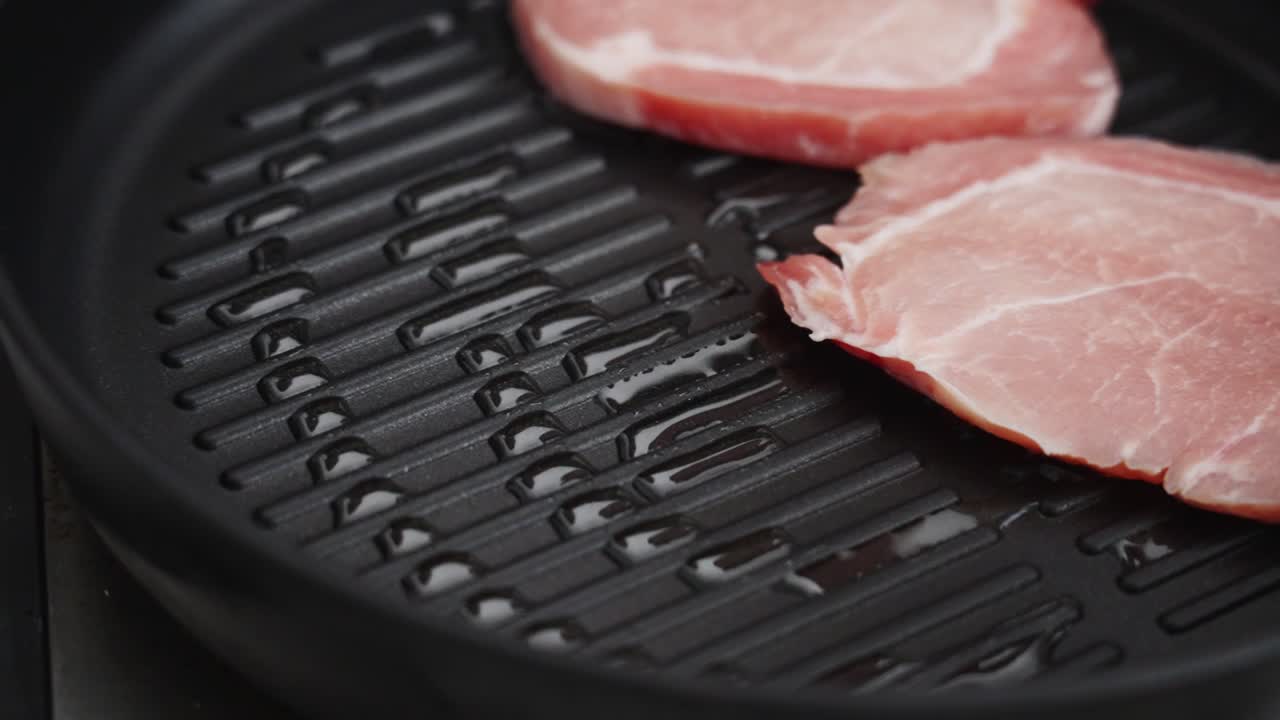 Crop person frying pork chops in pan in kitchen