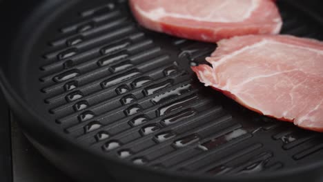 persona de la cosecha fritando chuletas de cerdo en la sartén en la cocina