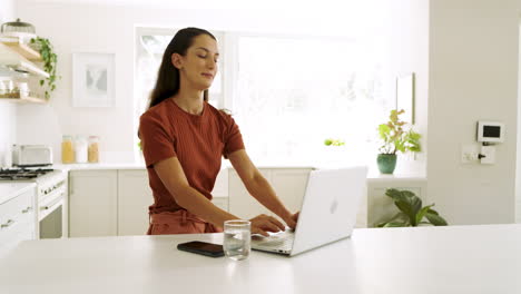 woman using laptop in bright kitchen, working from home with focus