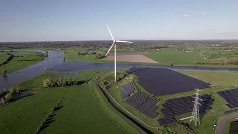 twentekanaal meets river ijssel valley approaching a windmill with rotating blades rising above solar panel field