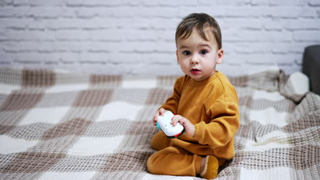 baby playing with a toy remote on a bed
