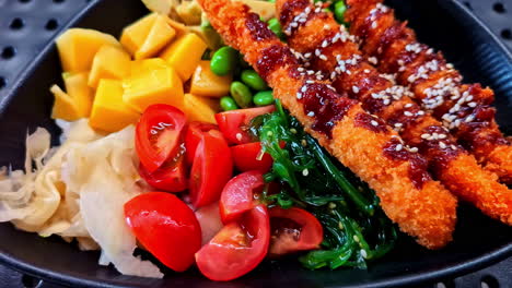 a close-up pull-out shot reveals a delicious and healthy poke bowl, beautifully presented with crispy prawn katsu, diced mango, edamame, seaweed salad, and fresh tomatoes on a bed of rice