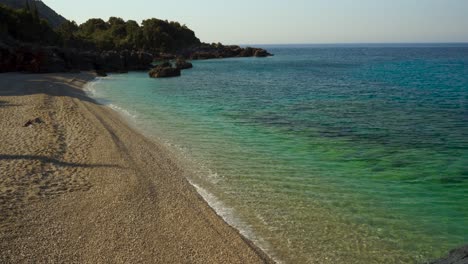 blue turquoise sea water washing pebbles of paradise rocky beach in ionian coastline, albania