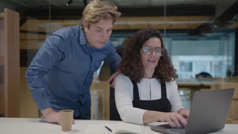 mid-aged businessman helping female colleague at work