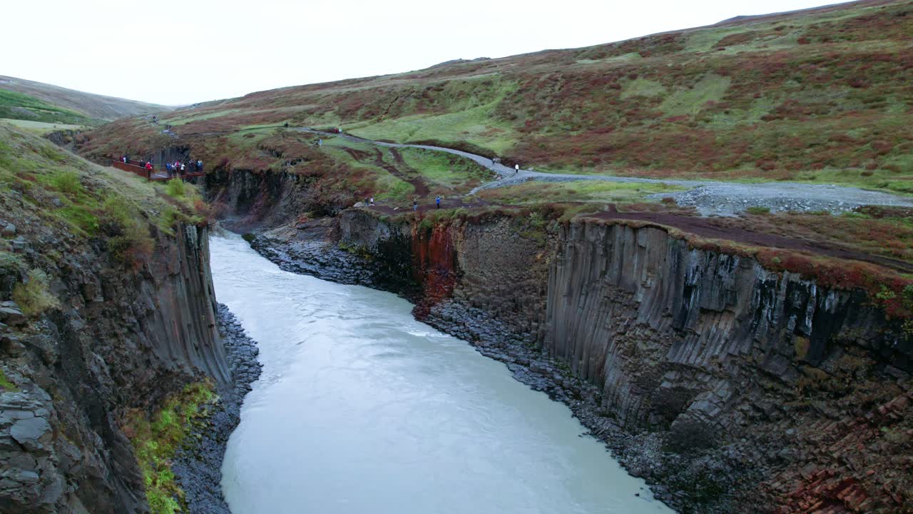 aerial: reversa a través del cañón del río studlagil con columnas de basalto en el noreste de islandia