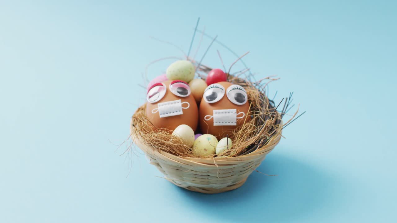 Video of eggs with eyes and face masks on a blue surface