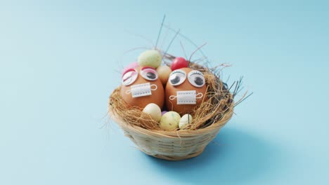 Video-of-eggs-with-eyes-and-face-masks-on-a-blue-surface