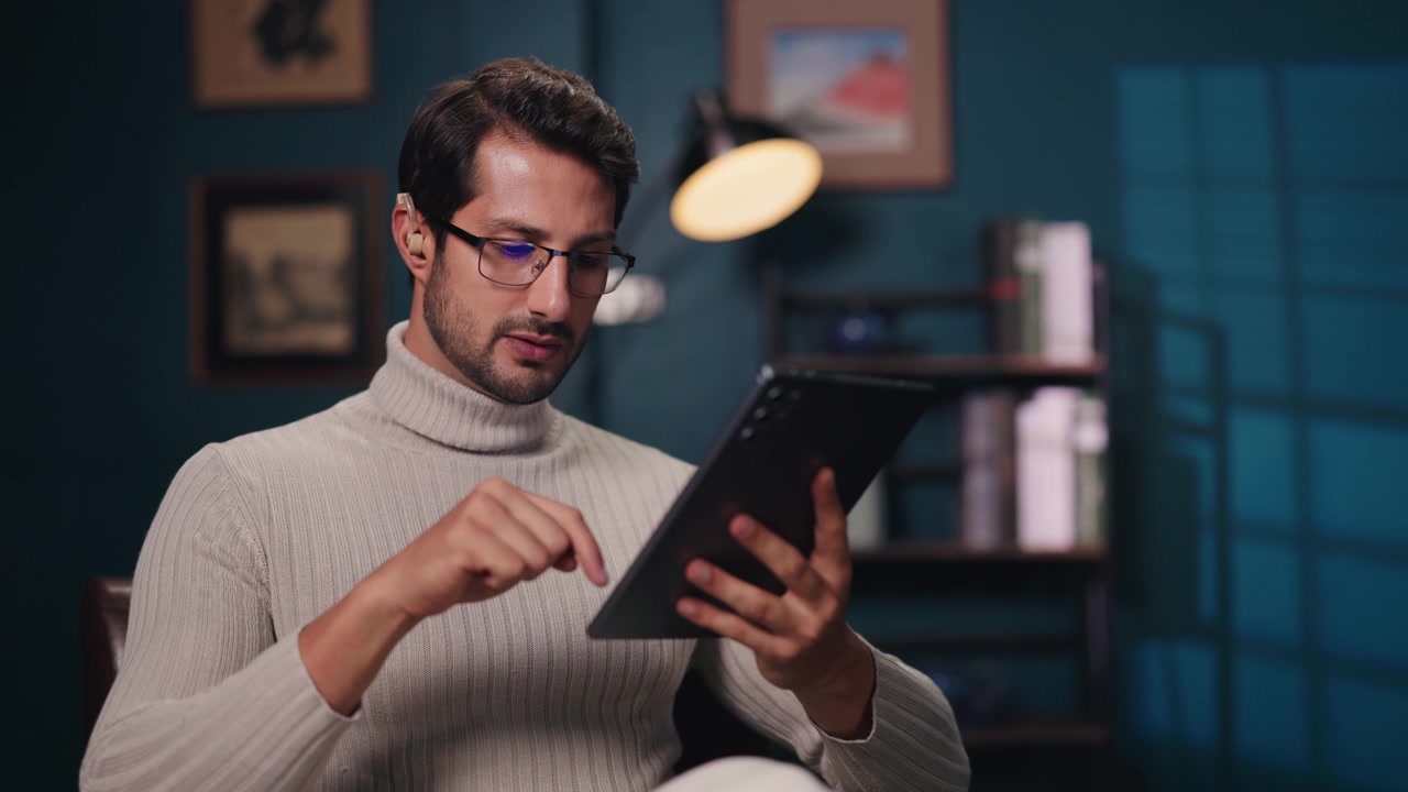 Young Man Using Digital Tablet in Dimly Lit Home Office