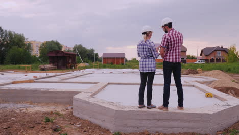 the customer of the future house communicates with the builder stand on the already built foundation