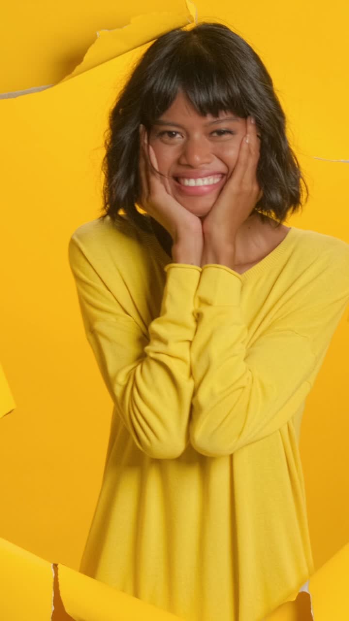 espressione gioiosa di una giovane donna in giallo vibrante contro uno sfondo luminoso
