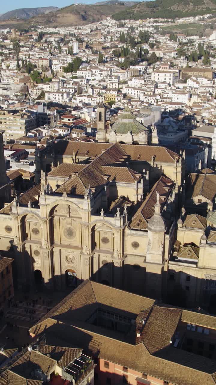 Vista aérea vertical mostrando la Catedral de Granada erigiéndose prominentemente sobre el paisaje urbano circundante en Granada, España.