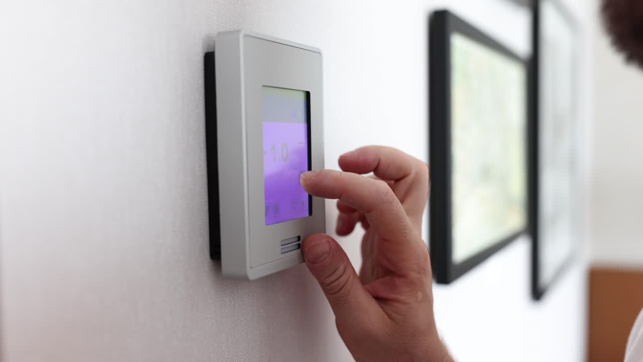 Person adjusting a smart thermostat for climate control