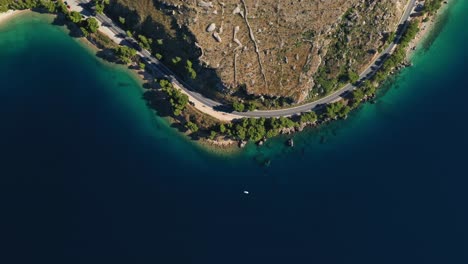 tomas aéreas con drones de camiones que circulan por una carretera costera en una península a lo largo de una hermosa bahía con aguas cristalinas