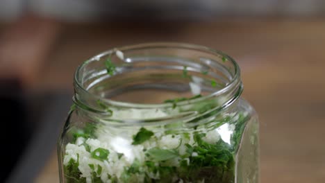 chef adds laurel leaf in jar with ingredients for the preparation of chimichurri