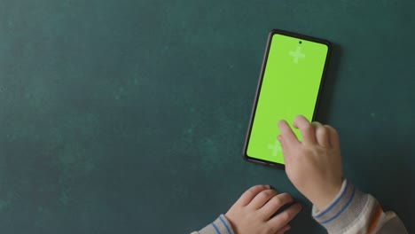 overhead studio shot of child using green screen mobile phone 4