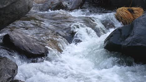 white water rushing in between rocks and boulders down a creek - close up