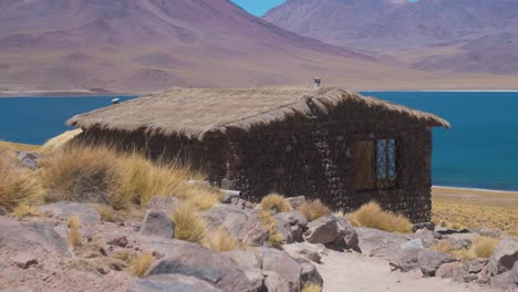 stone house in the desert next to lake surrounded by mountains day