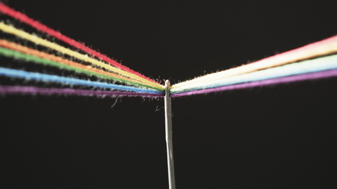 video de micro de hilos de color arco iris que pasan a través de la aguja con espacio de copia en fondo negro