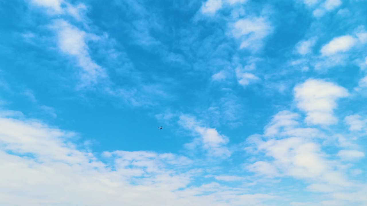 A serene view of the vast blue sky over China, with a small airplane dot flying through the clouds, capturing a peaceful moment in the sky. Concept of air transportation and traveling.