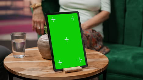 hombre y mujer ancianos hablando en su casa con una pantalla verde en la tableta