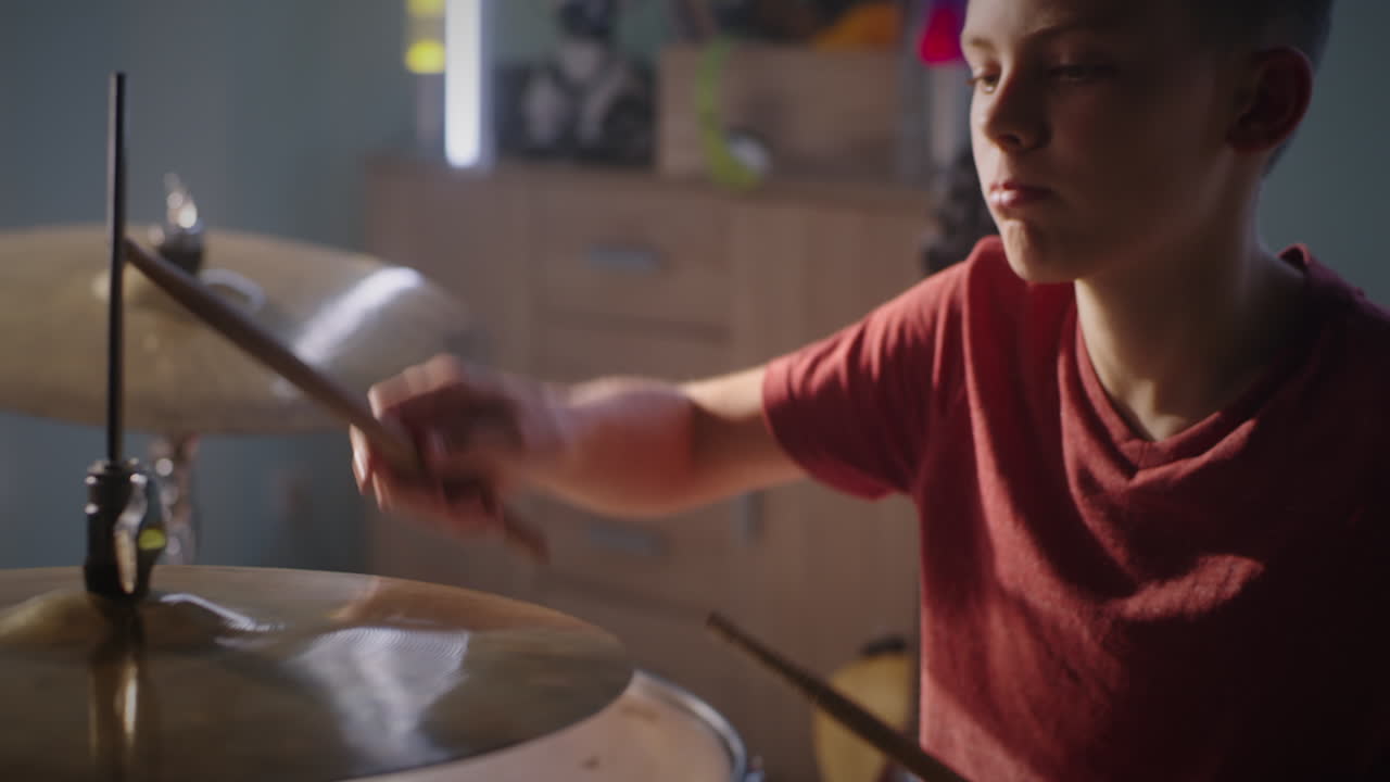 Teenager Learning to Play Guitar Low Angle of Concentrated Teenager with Pick Practicing to Play Electric Guitar while Sitting on Bed in Evening at Home