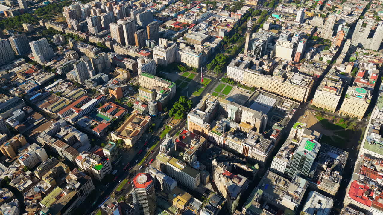 Aerial drone view of central Santiago showcasing government buildings, parks, and a grid of city streets bathed in sunlight
