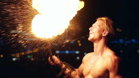 young blond male breathes out large stream of fire making fireball slow motion close-up shot