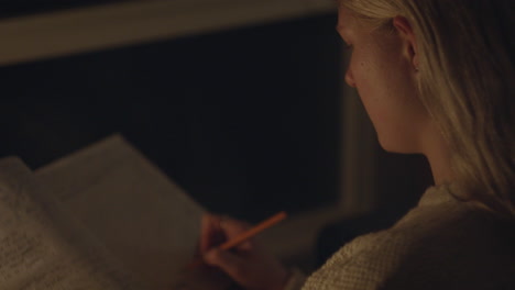a young woman writes in her journal, her face softly lit by candlelight, immersed in deep reflection and personal expression.